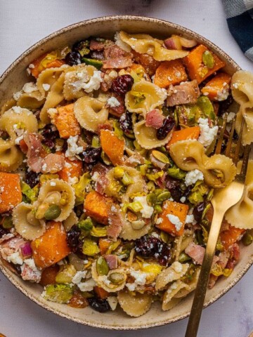 Fall pasta salad with roasted vegetables in a bowl with a gold fork.