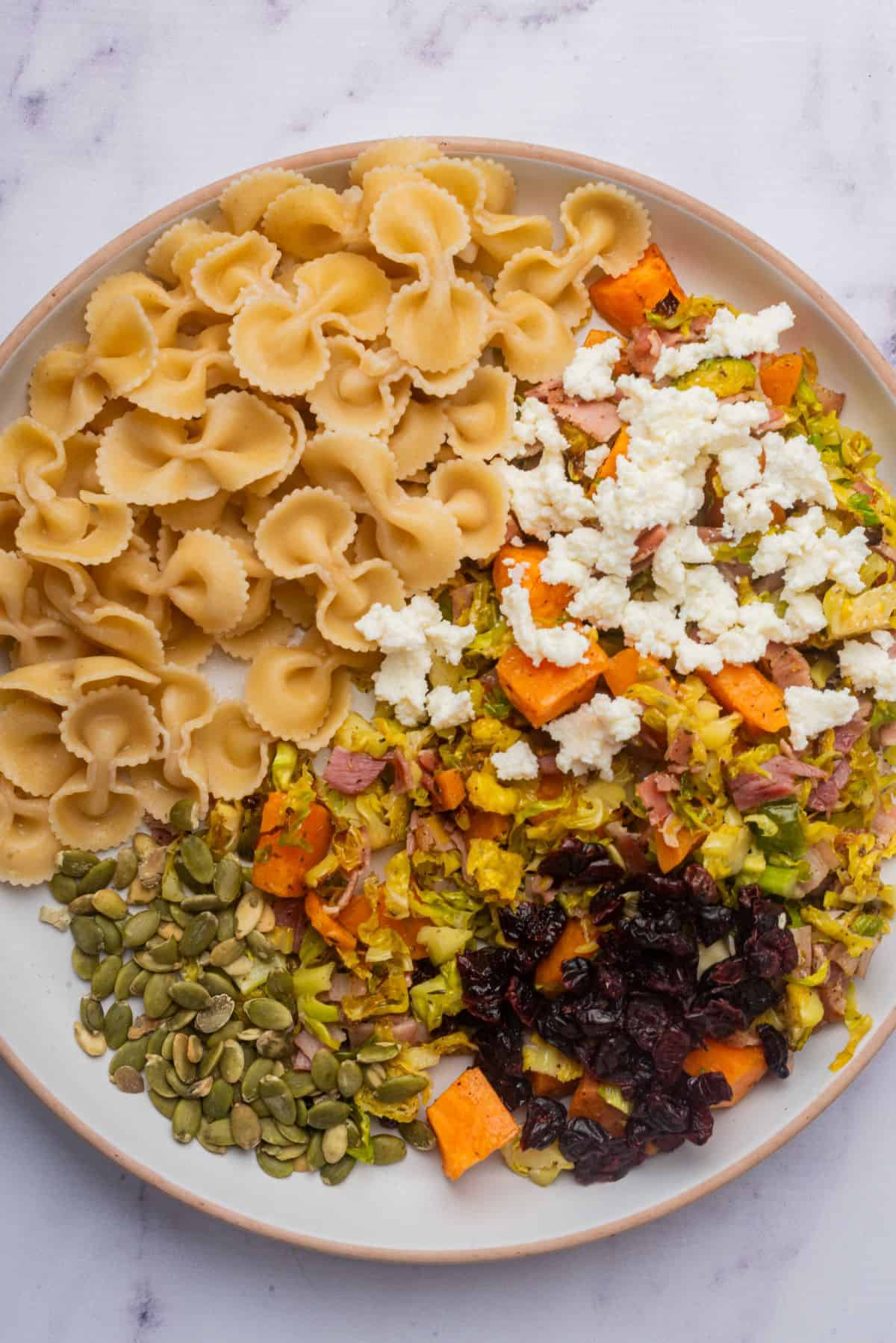 Each ingredient for Thanksgiving pasta salad is in a large serving bowl.