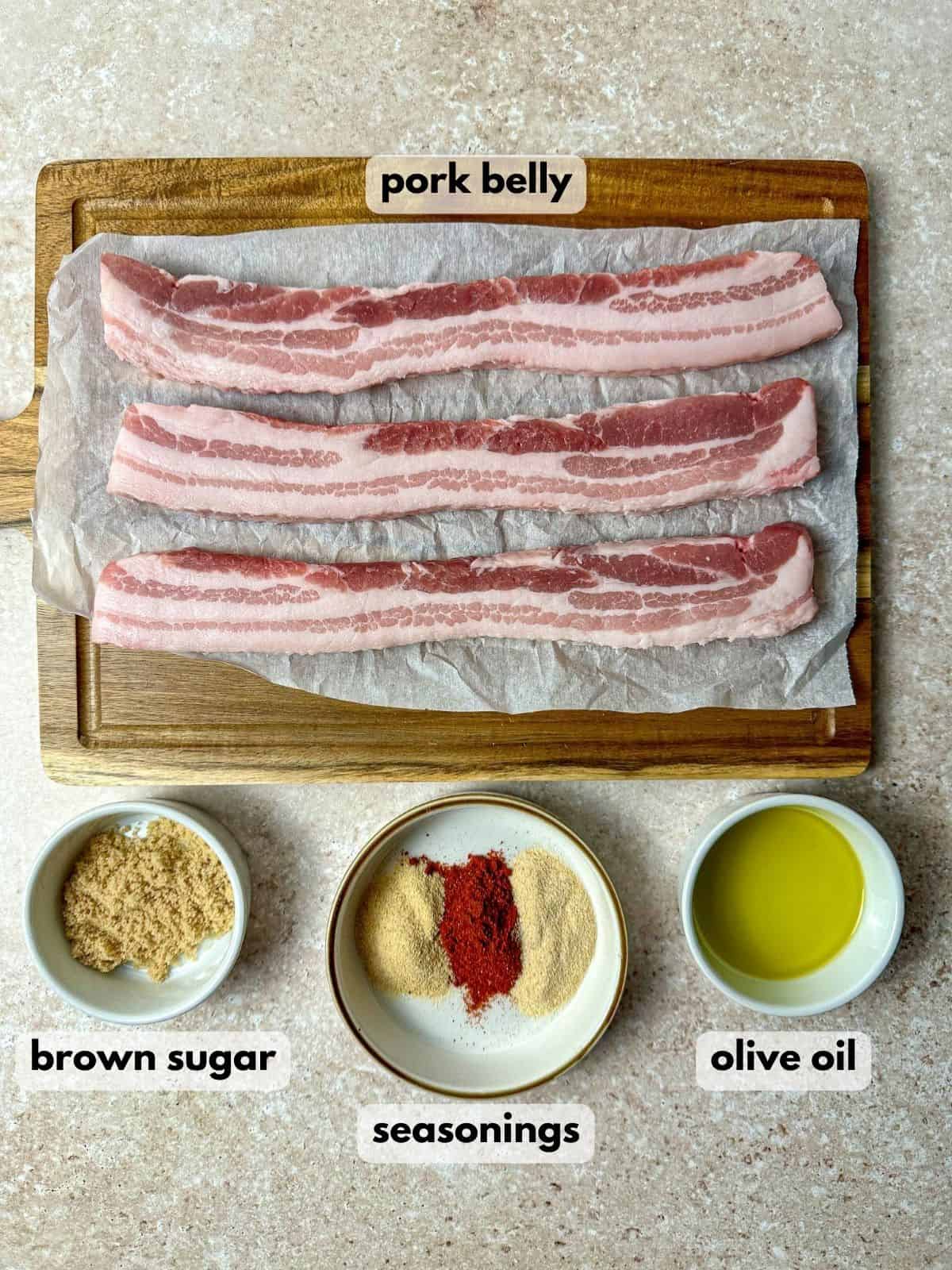 Ingredients needed to make air fryer pork belly include sliced pork belly, a bowl of brown sugar, seasonings, and olive oil.