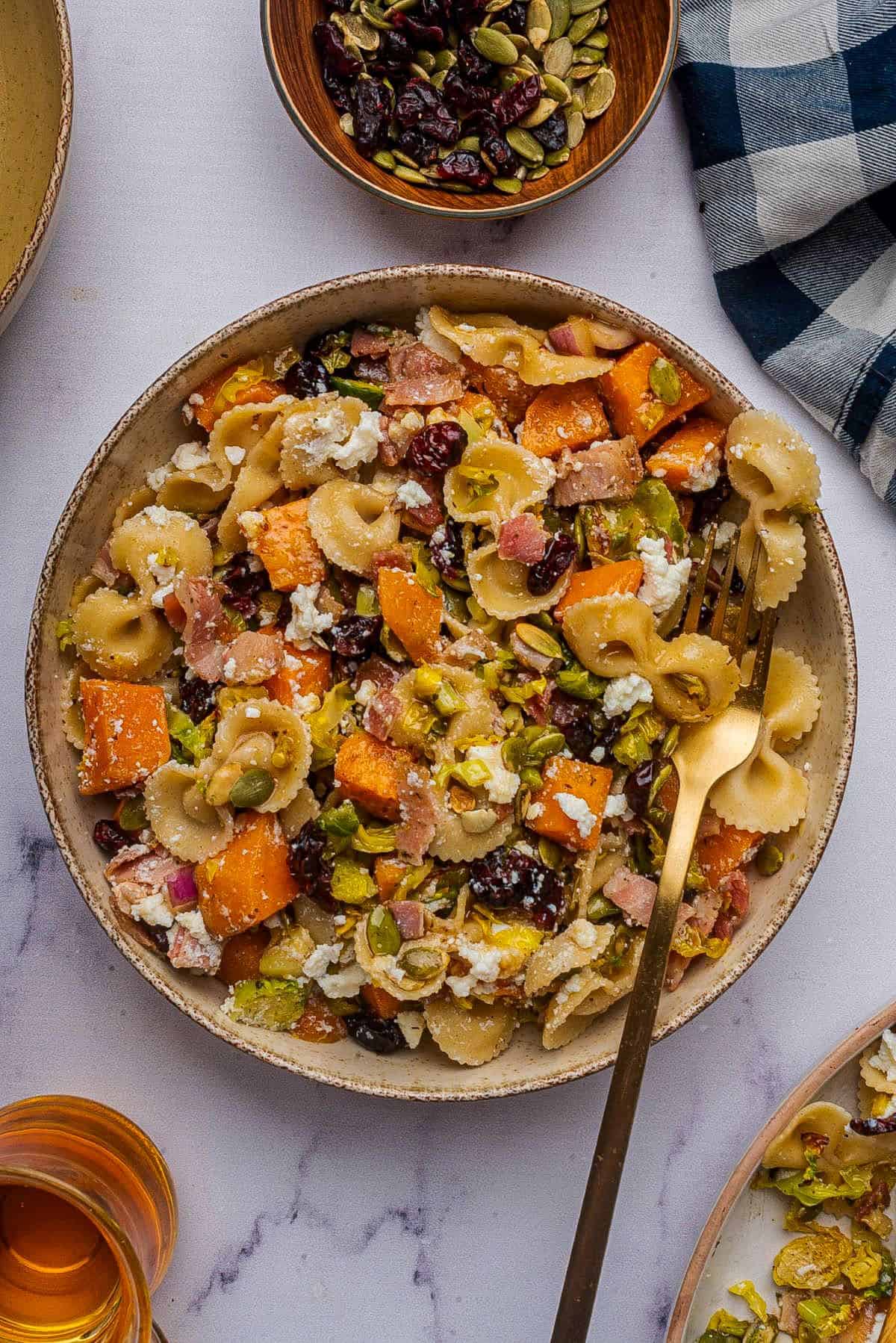 Fall pasta salad with roasted vegetables in a bowl with a gold fork.