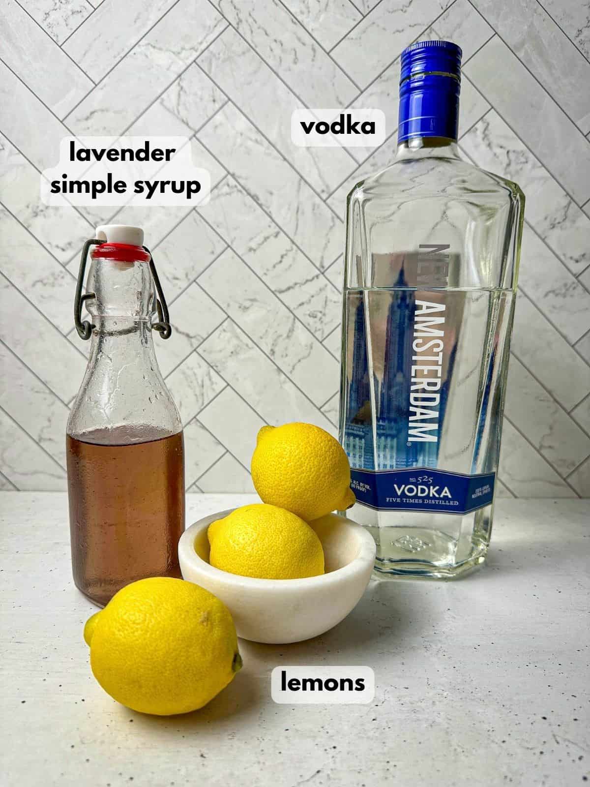 Ingredients needed to make a lavender martini include a bottle of vodka, jar of lavender syrup, and lemons.