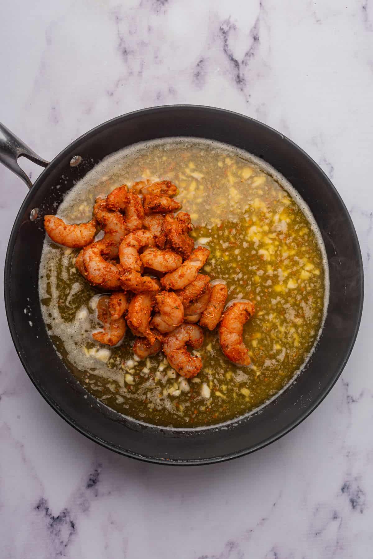 Cajun shrimp added to a skillet with a butter, garlic, and white wine sauce.