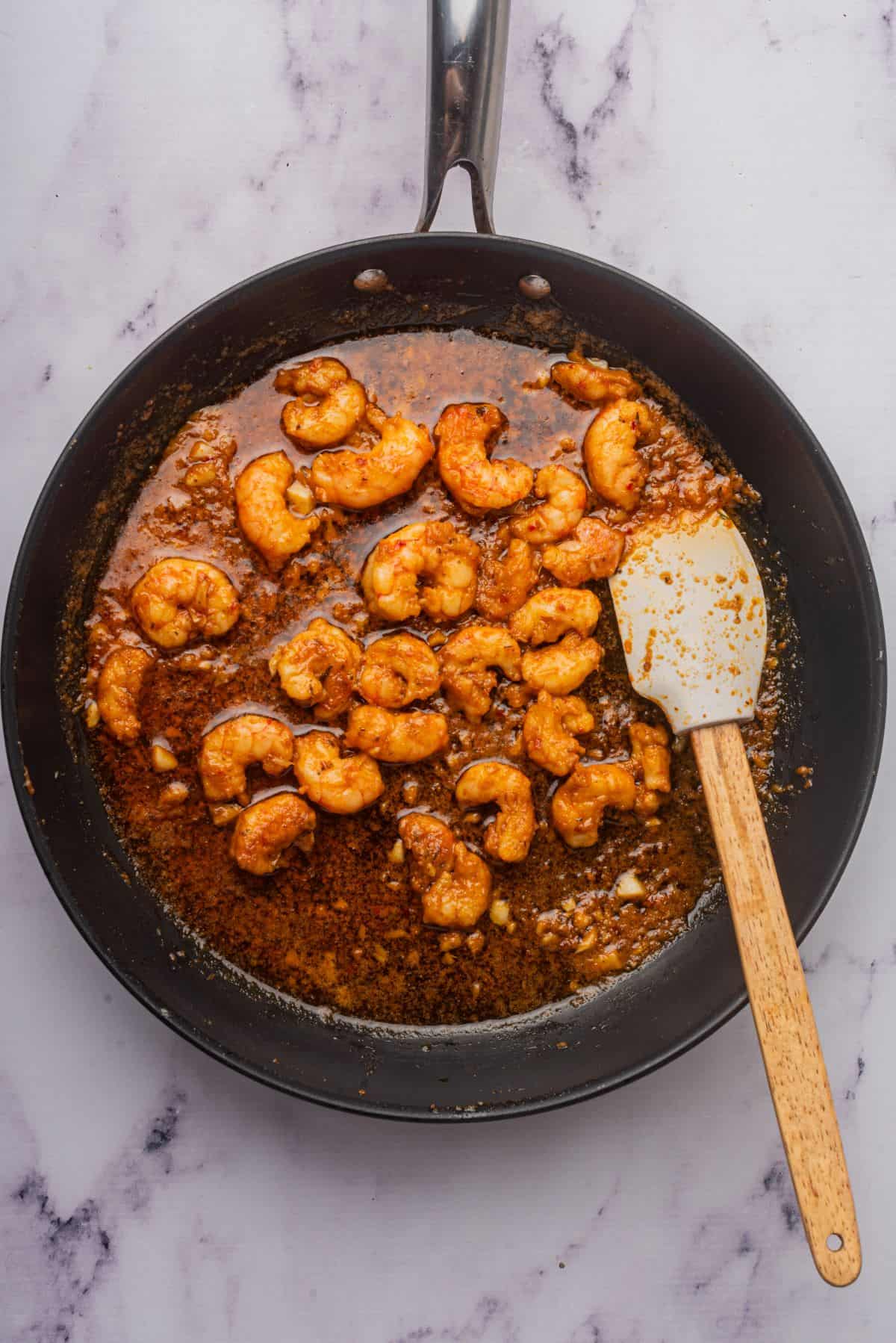 Cajun shrimp scampi in a skillet with a spatula.