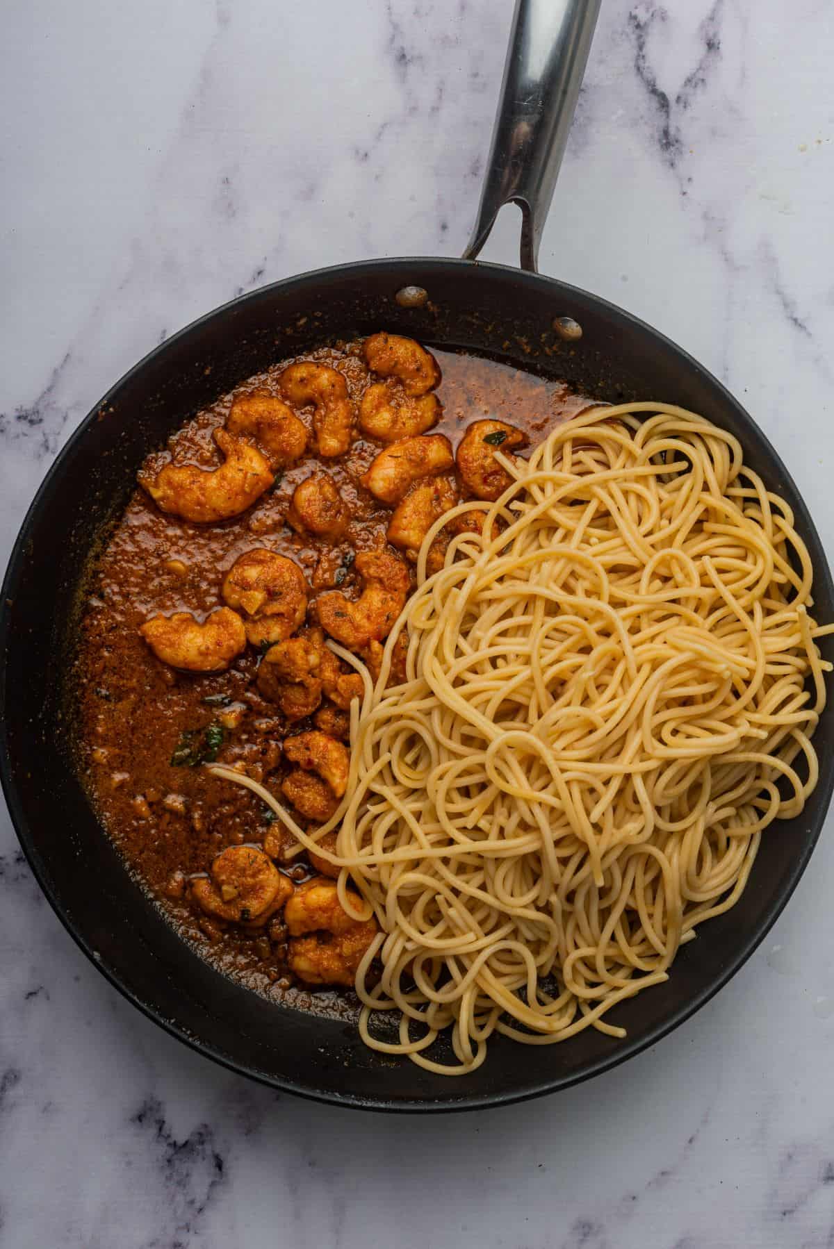 Spicy shrimp pasta recipe in a skillet with spaghetti.