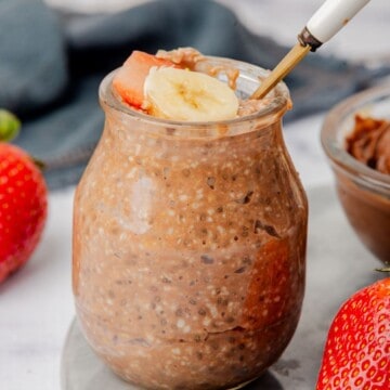 Nutella overnight oats in a jar with sliced banana and strawberry.