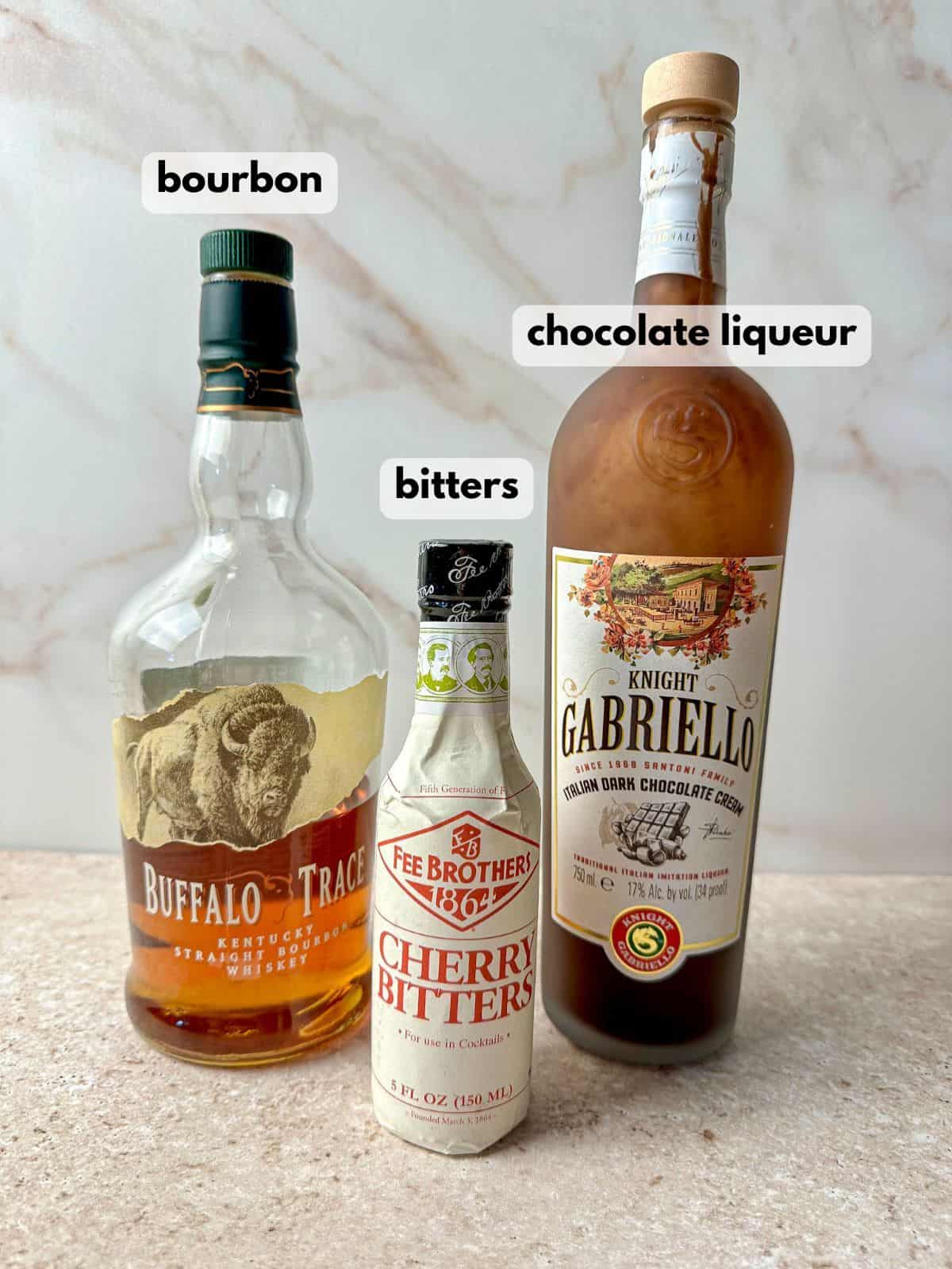 A bottle of bourbon and chocolate liqueur with a bottle of bitters.