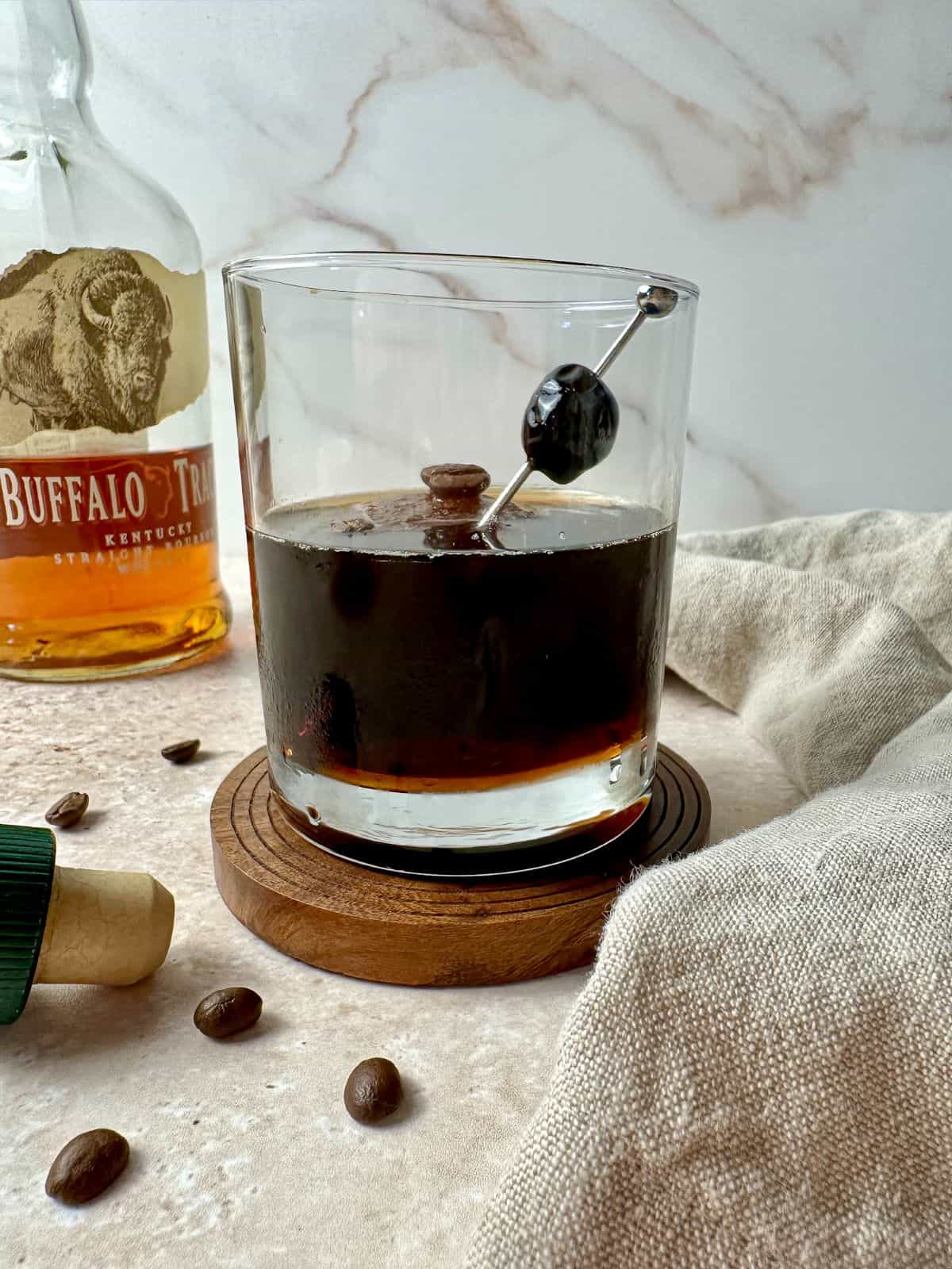 Coffee old fashioned in a rocks glass with a cherry and coffee beans for garnish.