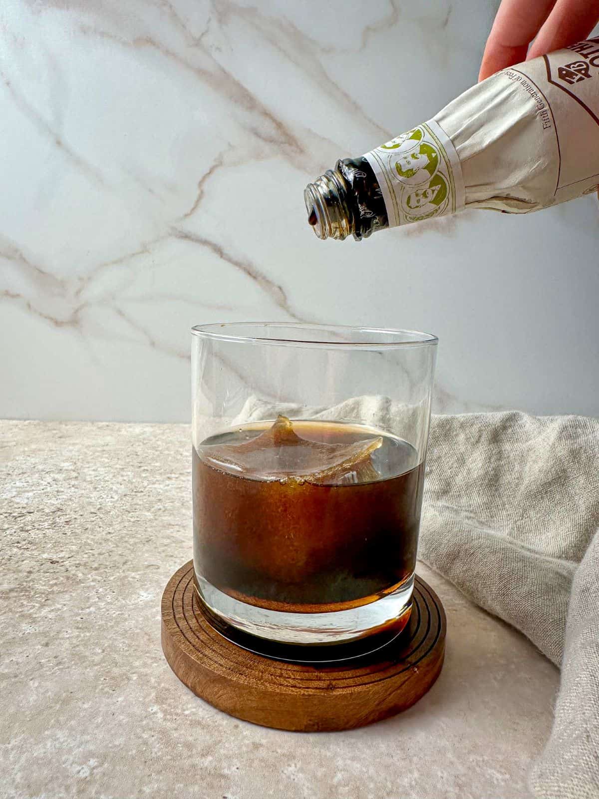 Adding bitters to a cocktail with coffee and bourbon.