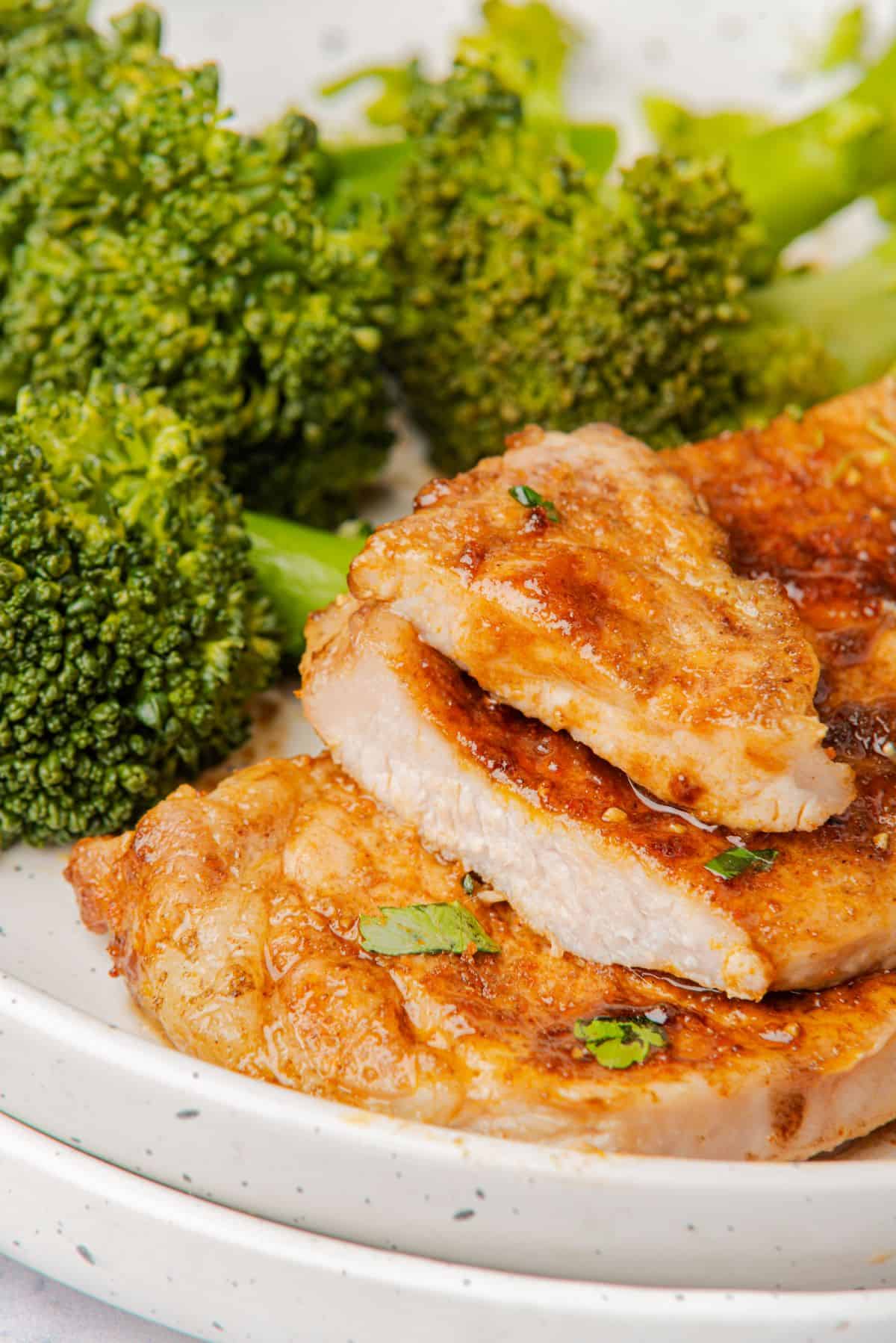 Two thin pork chops with one sliced open to show a juicy interior.