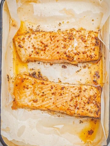 Baked blackened salmon in a baking dish with parchment paper.