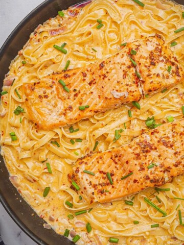 Cajun salmon pasta in a skillet topped with chives.