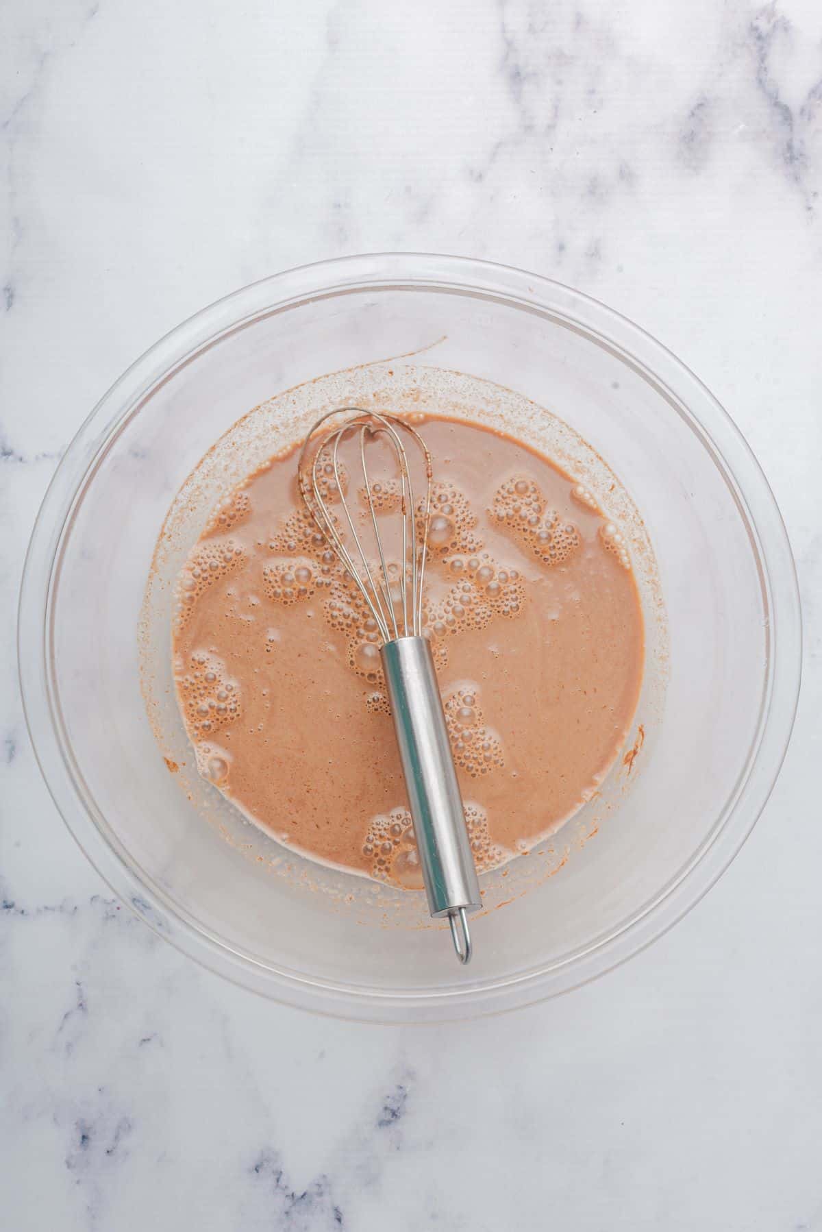 A bowl of milk, Nutella, and honey whisked with a whisk.