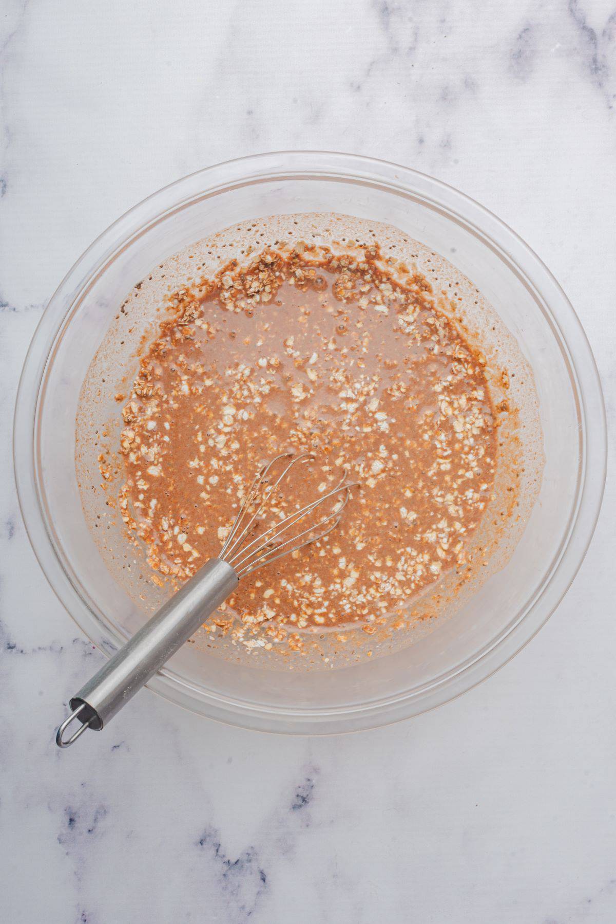 Ingredients of Nutella oatmeal mixed in a bowl with a whisk.