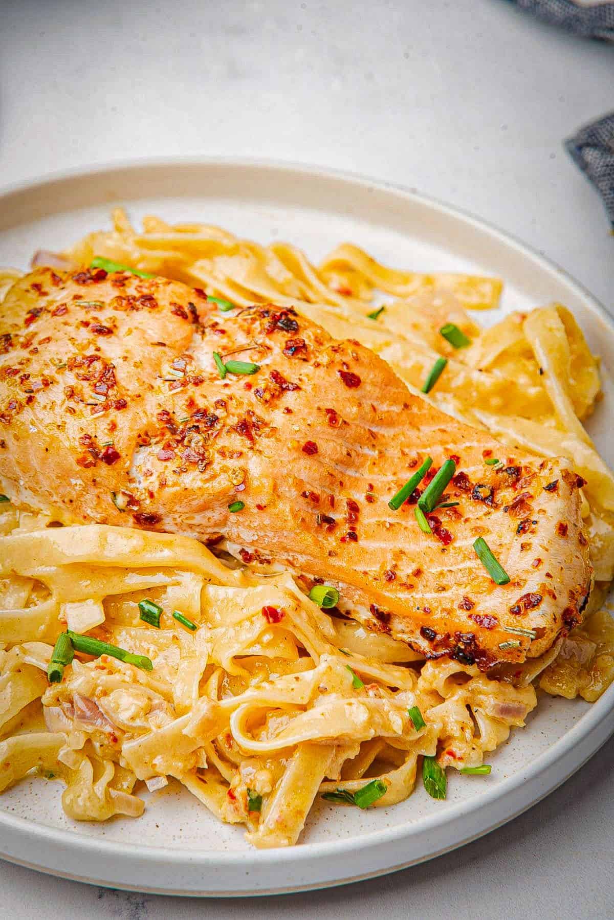 Blackened salmon baked and placed on top of a bed of pasta.