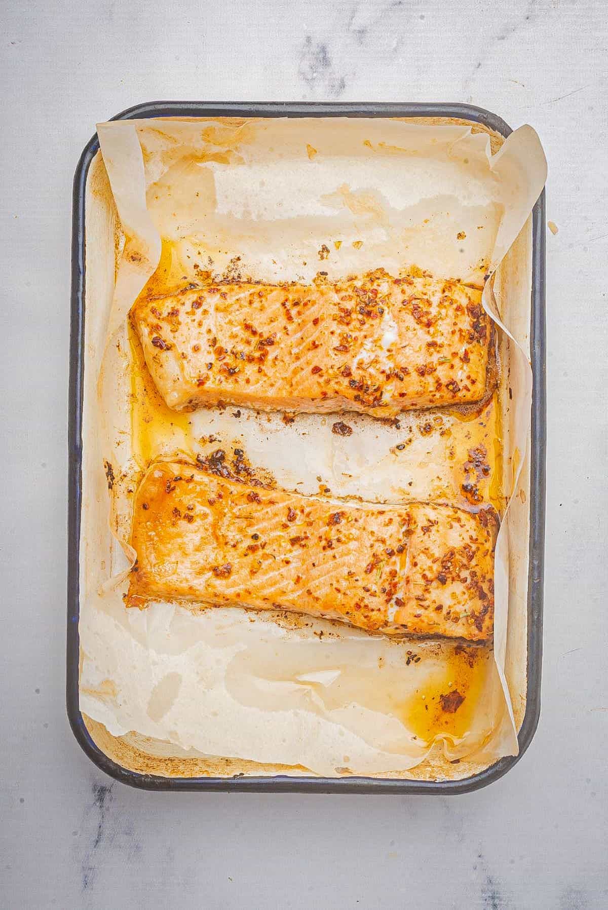 Baked blackened salmon in a baking dish with parchment paper.