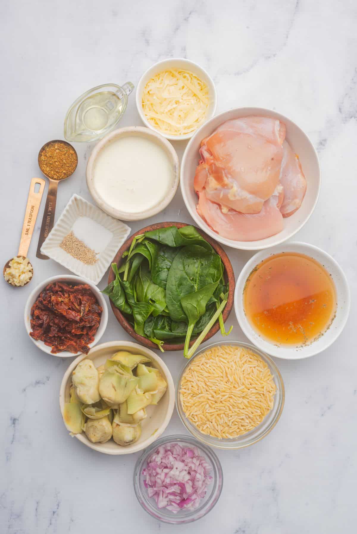 Ingredients needed to make chicken and orzo bake are on a marble countertop.