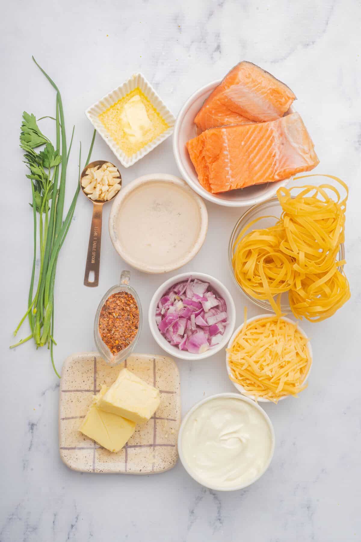 Ingredients needed to make this Cajun salmon pasta recipe are in bowls on a countertop.