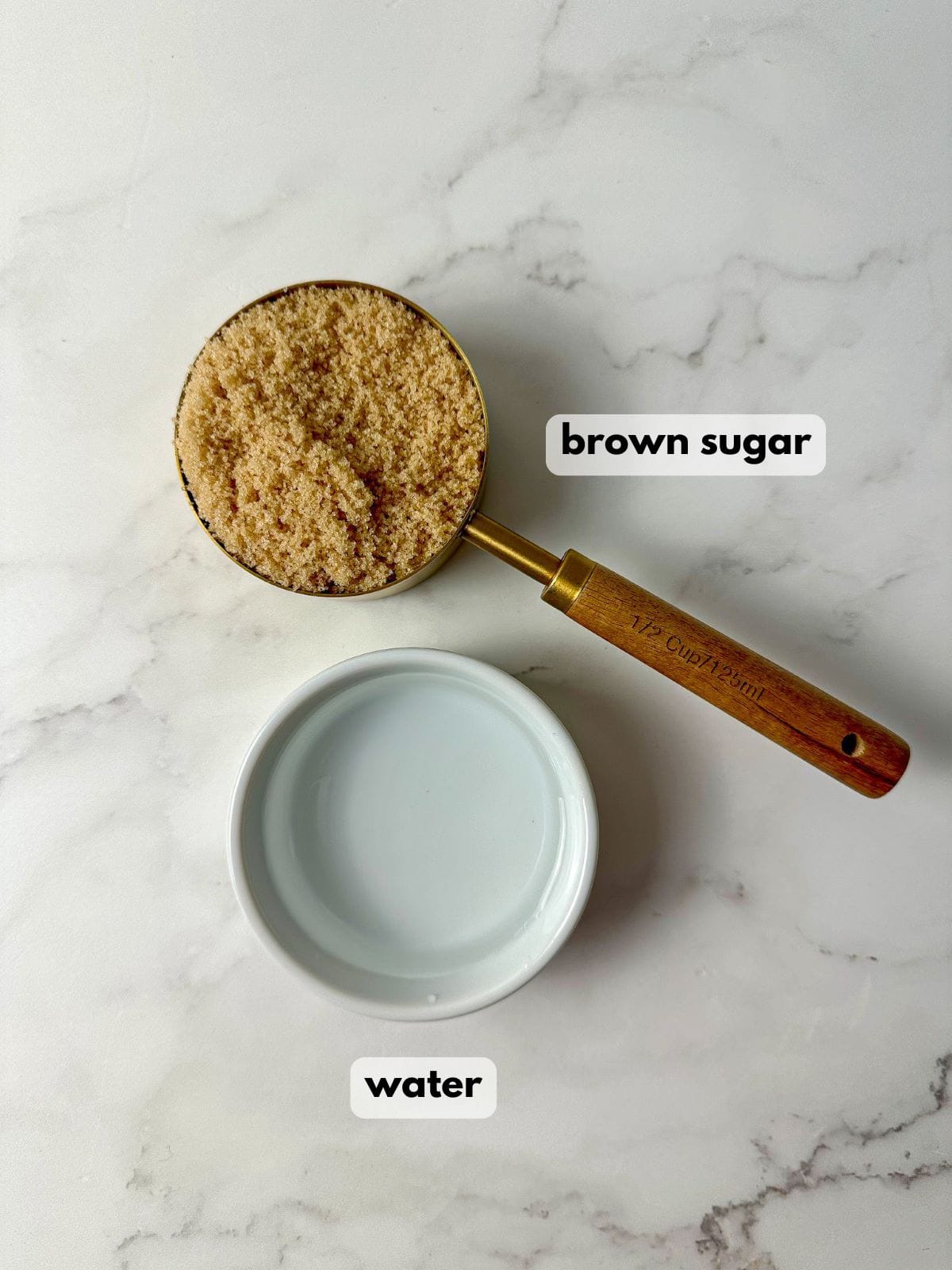 A bowl filled with water and a measuring cup with brown sugar.