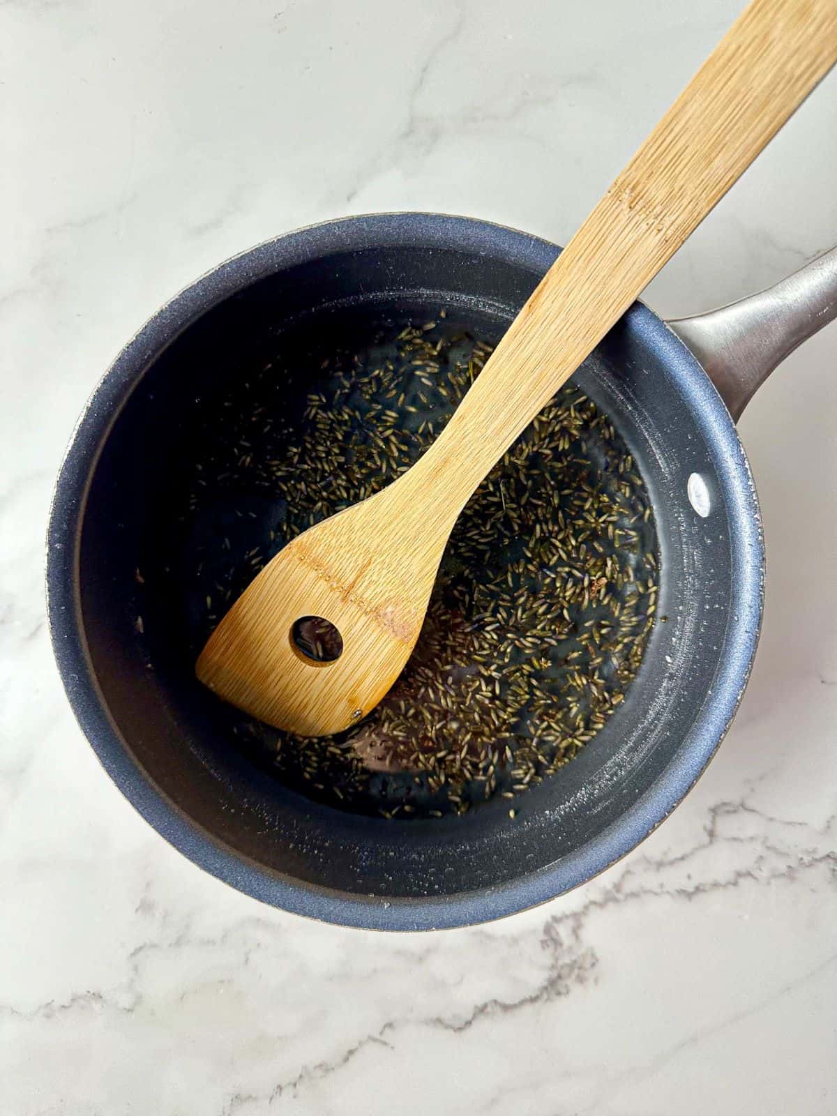 Lavender syrup in a saucepan with a wooden spoon.