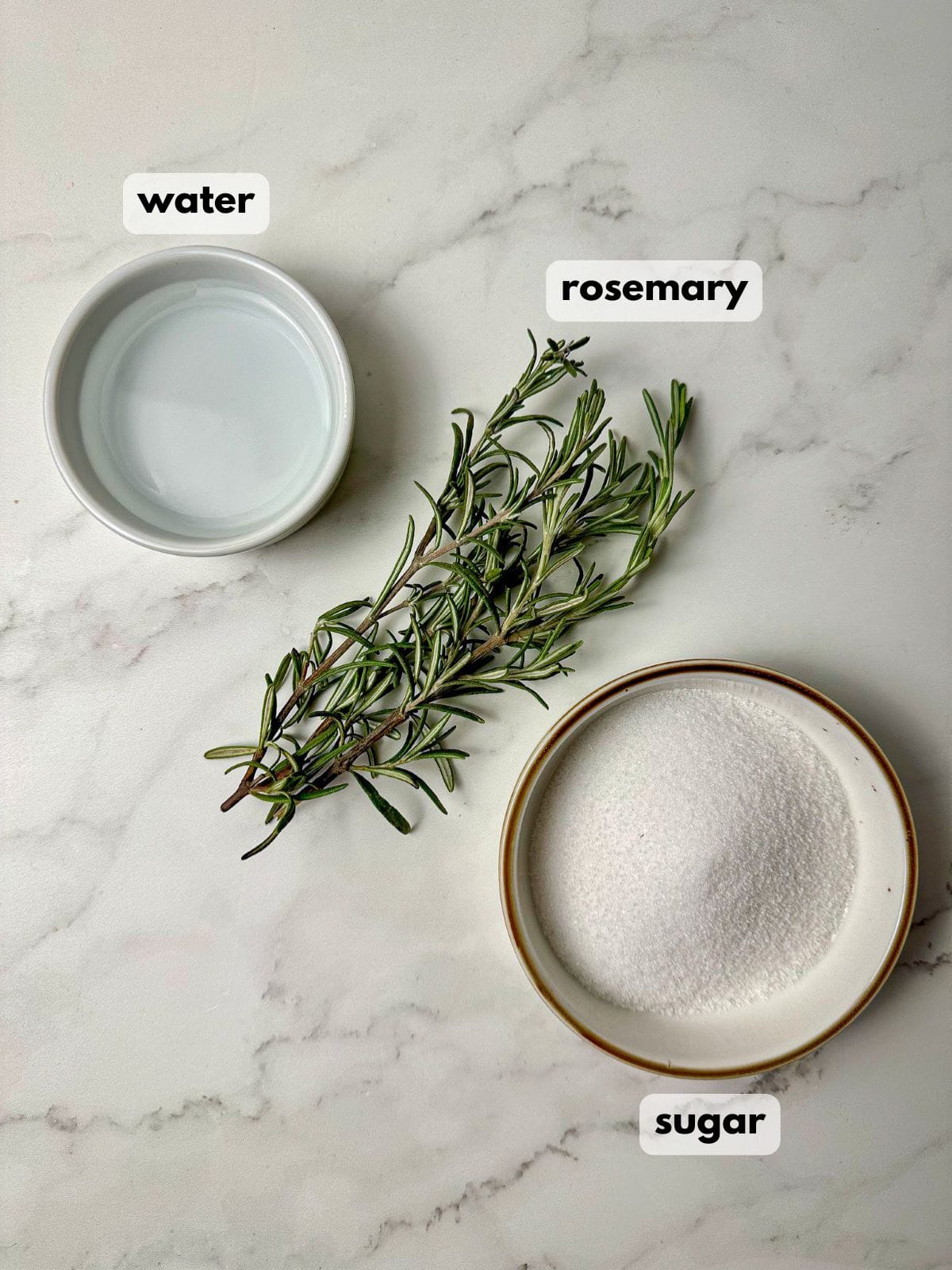 Bowls with white sugar, water, and fresh rosemary.