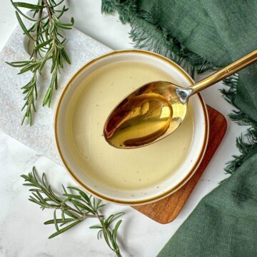 Homemade rosemary simple syrup recipe in a bowl with a spoon.