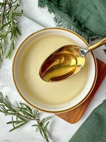 Homemade rosemary simple syrup recipe in a bowl with a spoon.