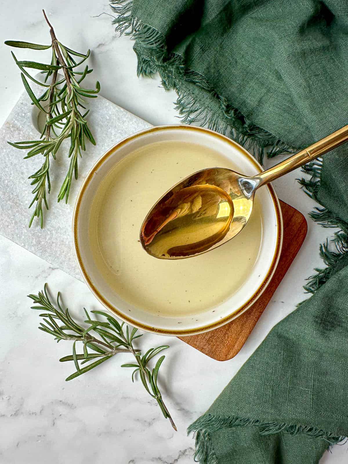 Homemade rosemary simple syrup recipe in a bowl with a spoon.