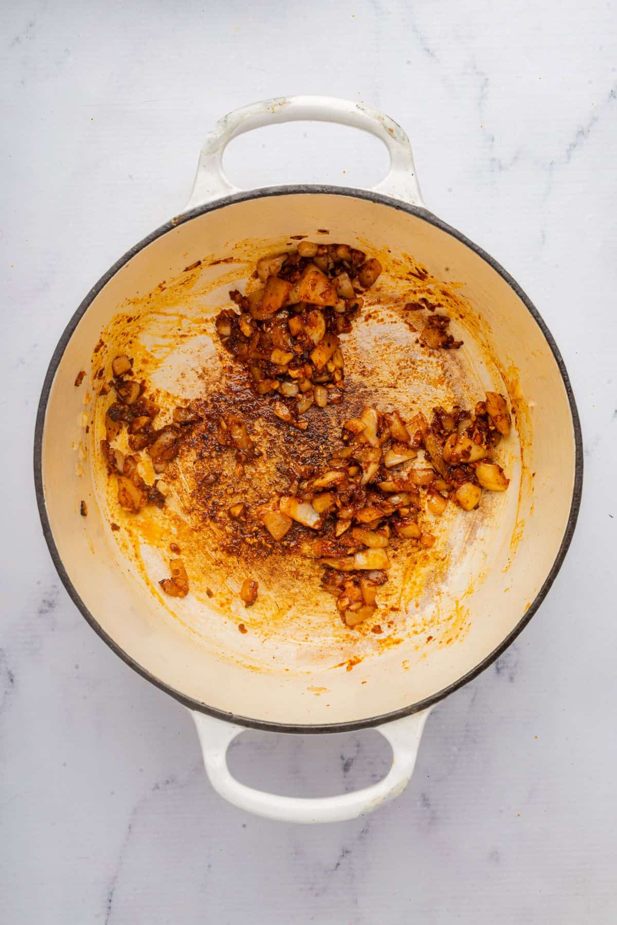 Onions, garlic, and spices sauteing in a Dutch oven.