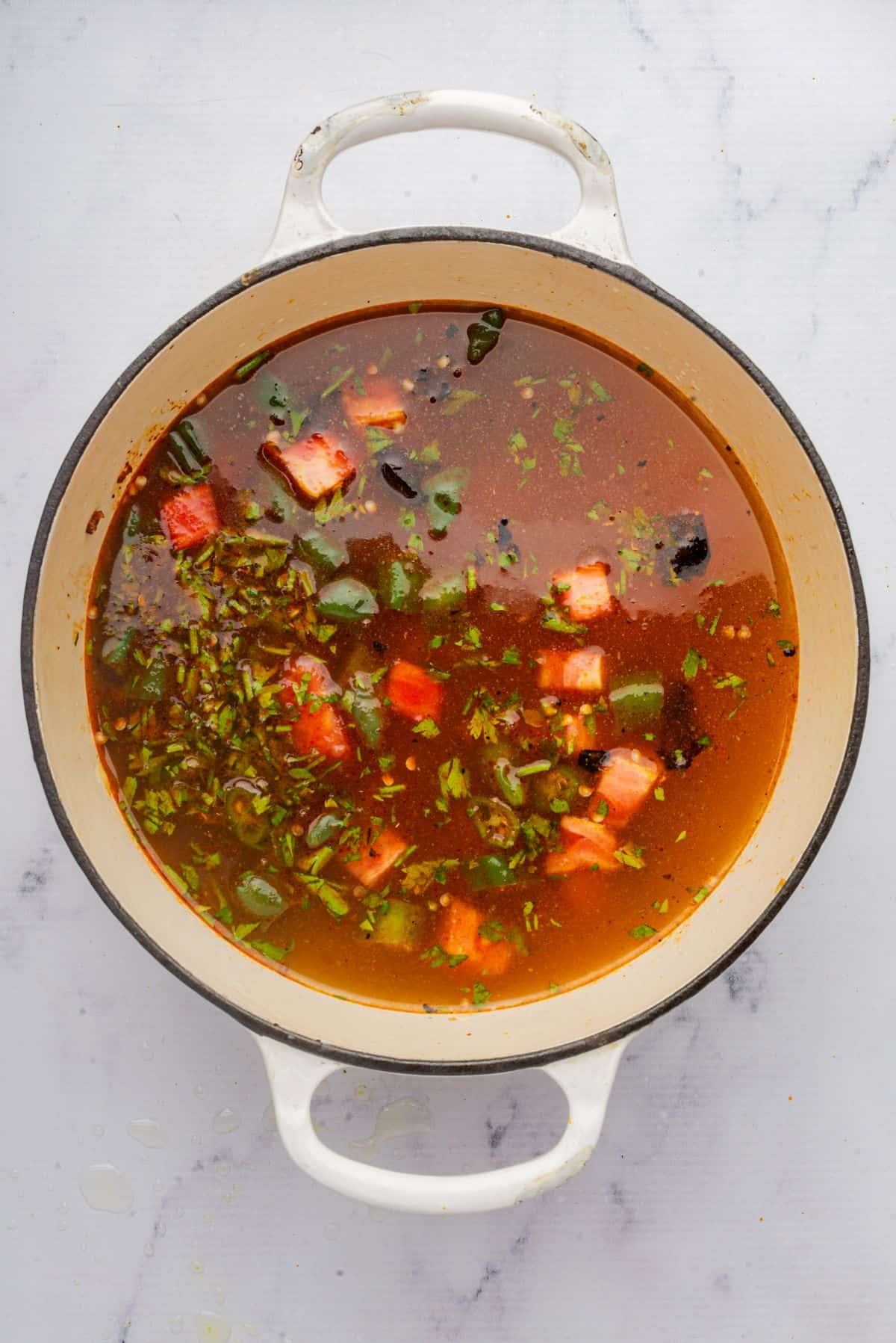 Chicken broth, tomatoes, and cilantro cooking in a large pot.