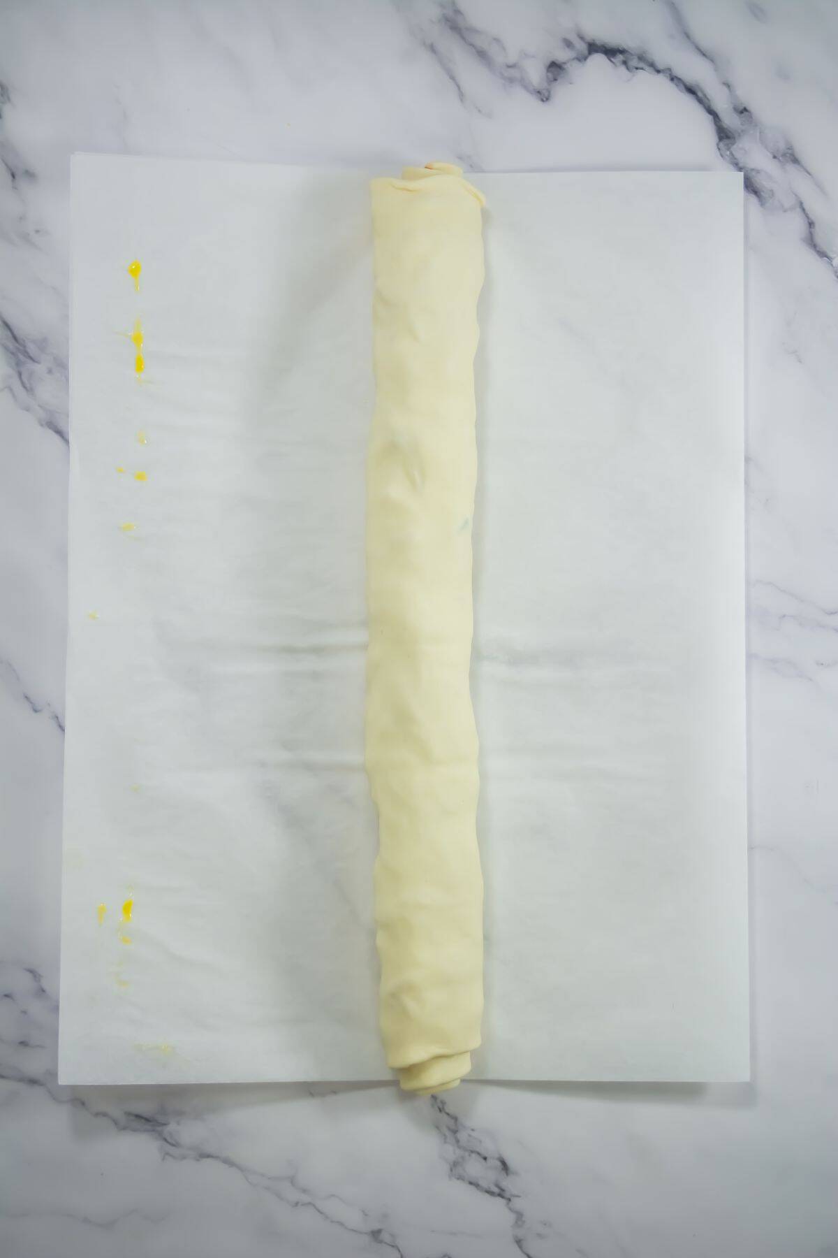 Puff pastry rolled on parchment paper.