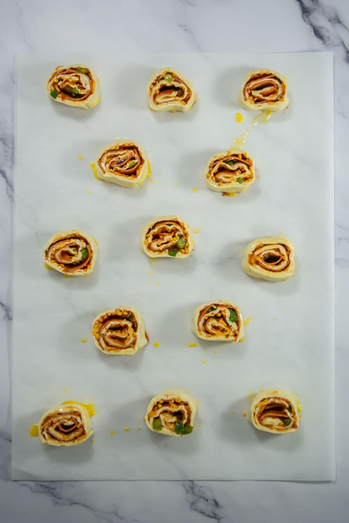 Pepperoni pizza pinwheels sliced on parchment paper.