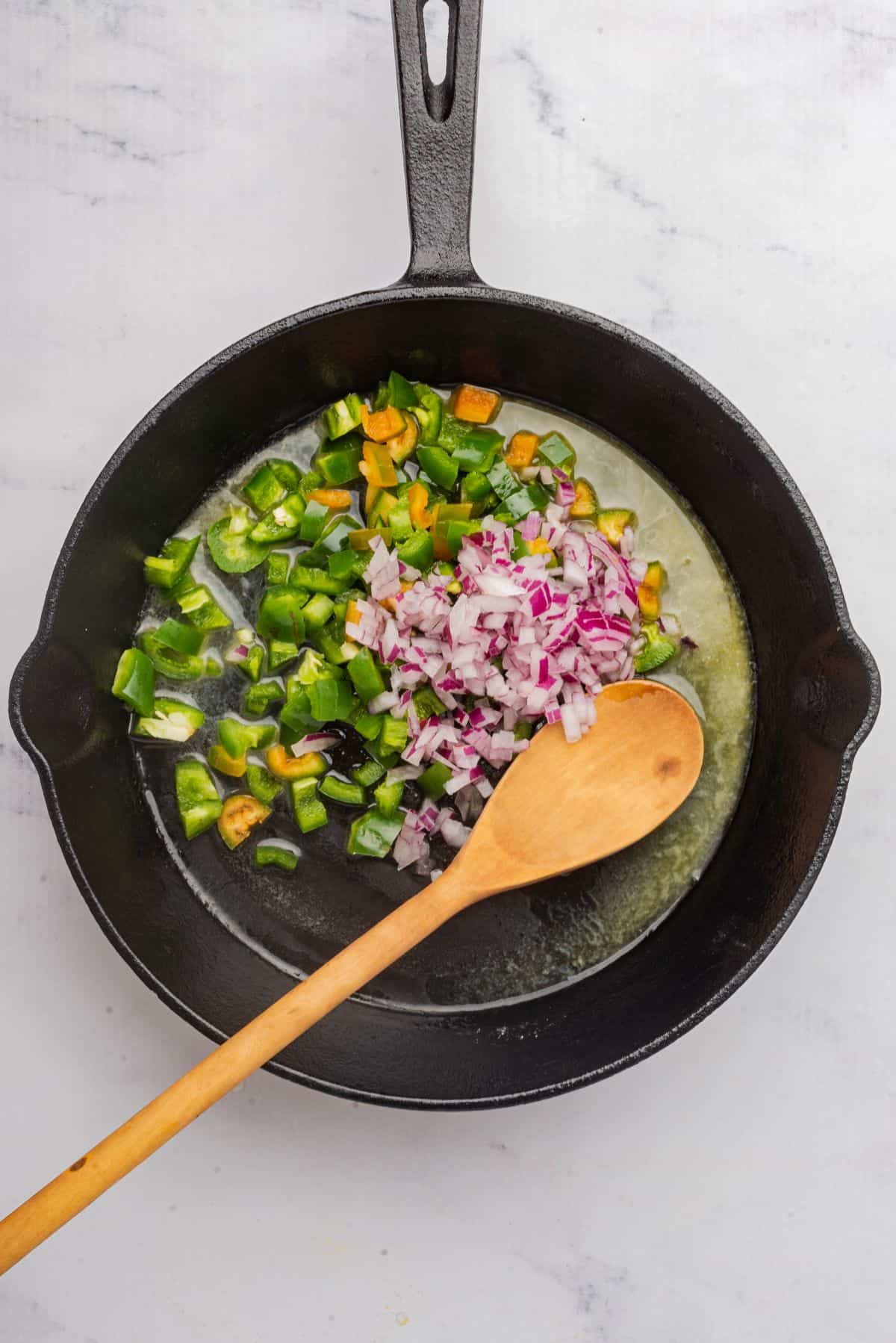 Diced jalapenos and shallot sauteing in a skillet.