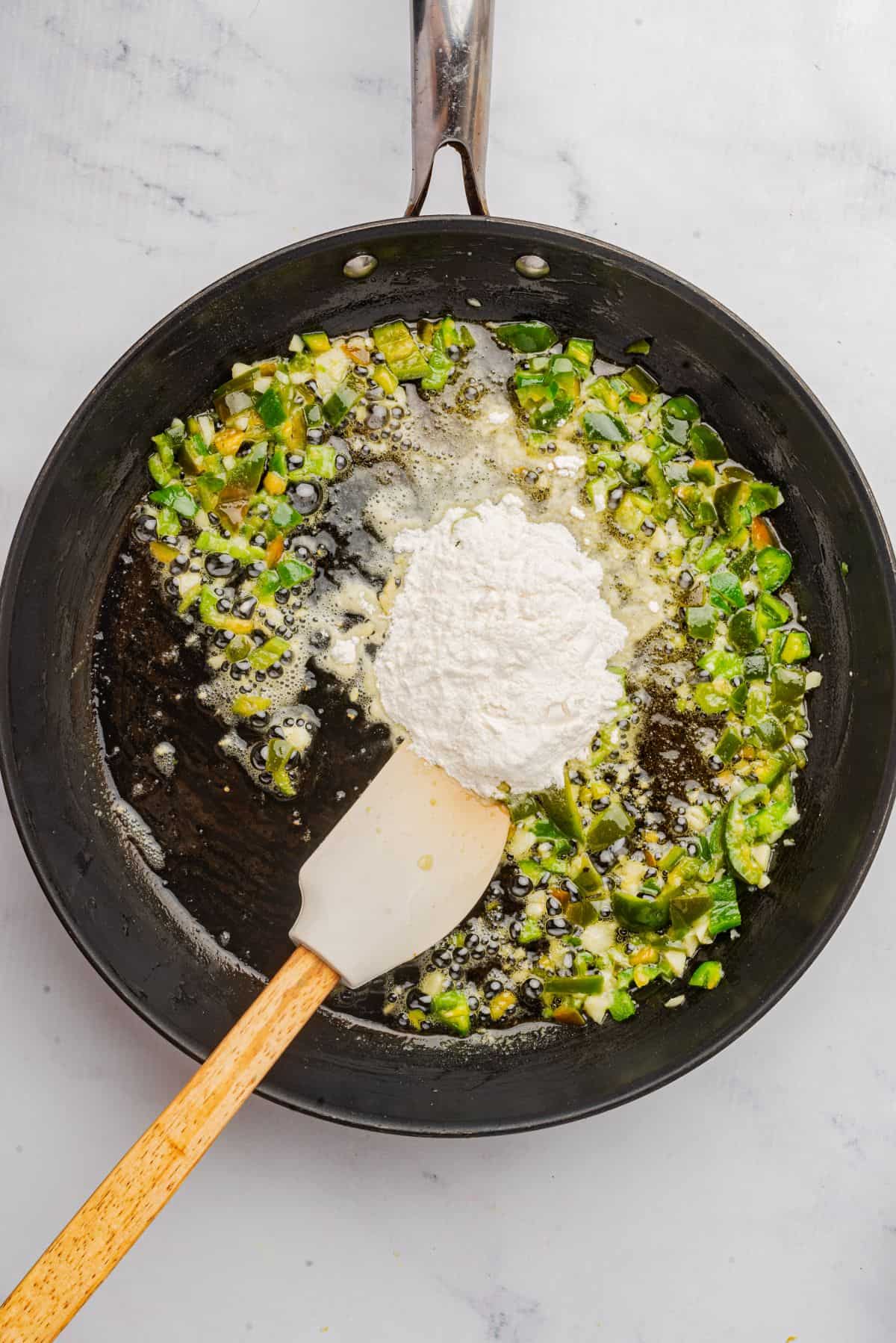 Butter, diced jalapenos, and garlic sauteing in a skillet with flour added.