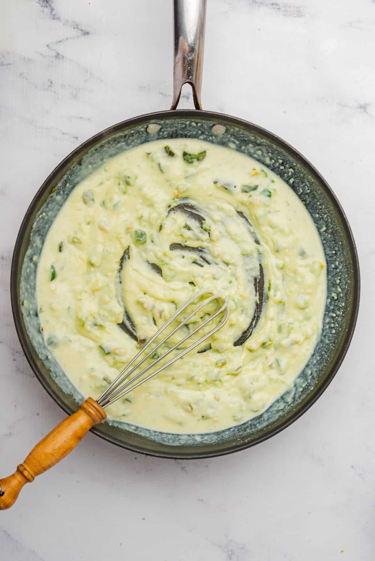 Whisking mac and cheese roux in a skillet.