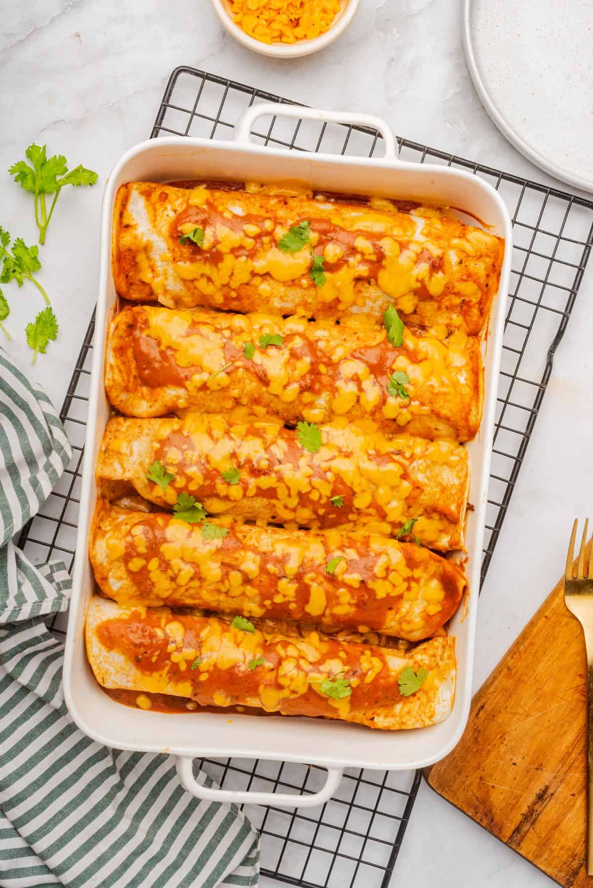 Baked beef brisket enchiladas in a baking dish topped with cheese and cilantro.