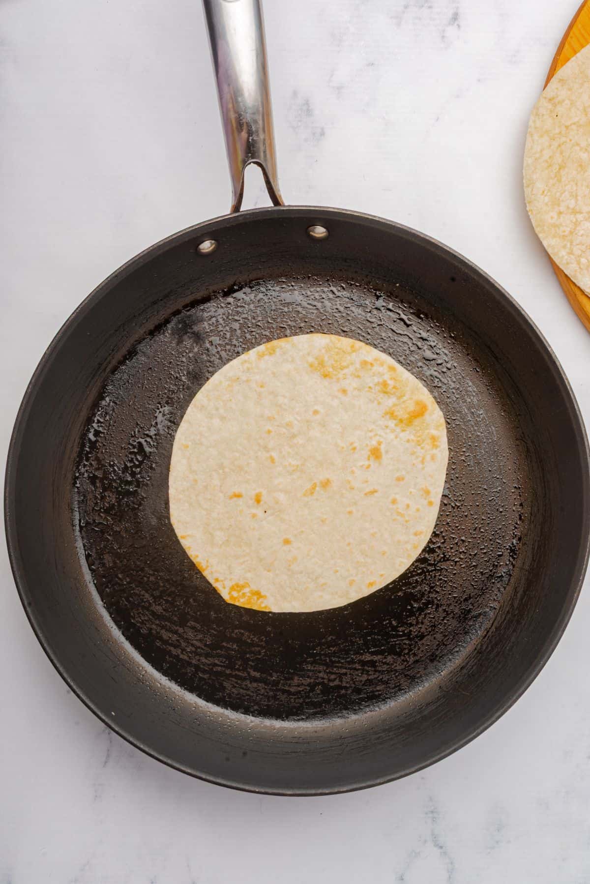 A flour tortilla on a skillet.