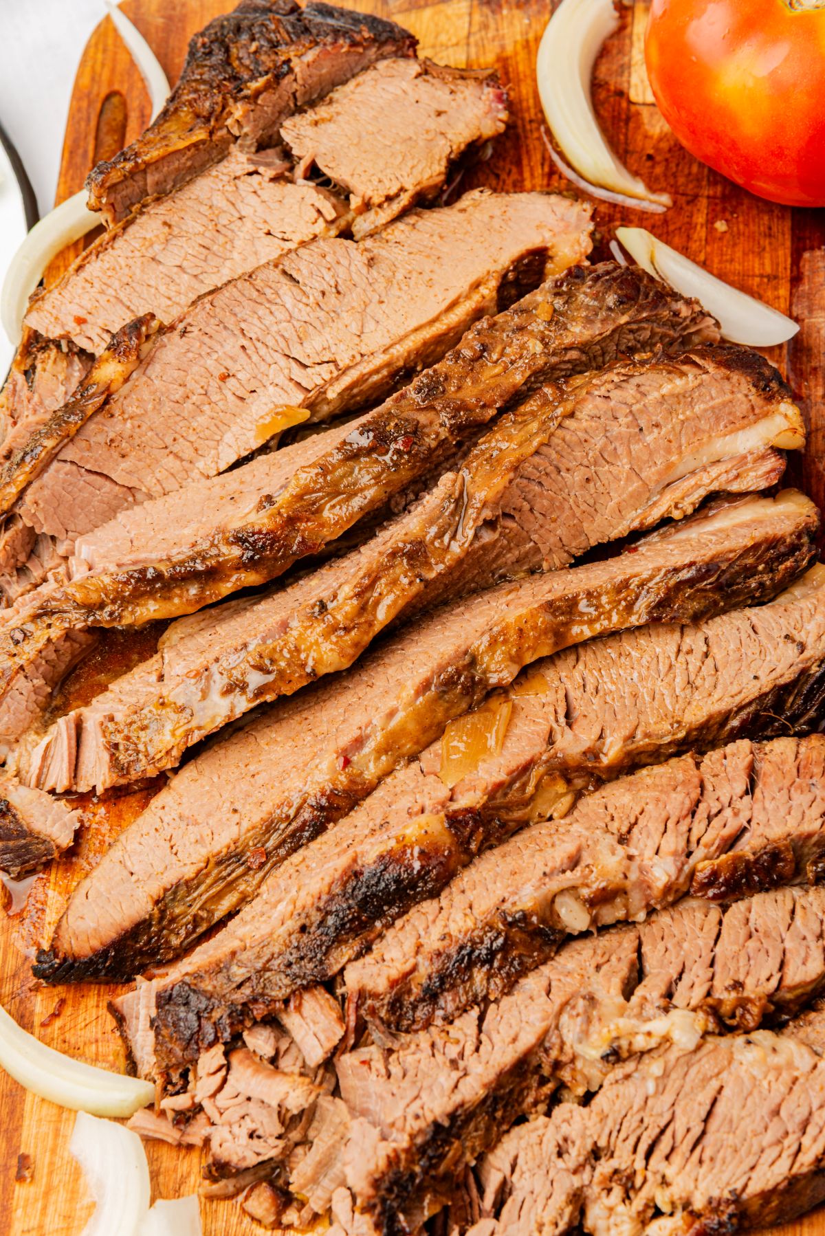 Thinly sliced braised beef brisket on a cutting board.