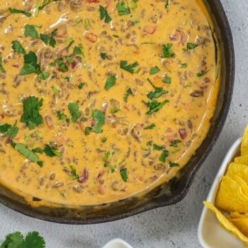 Ground beef queso dip with Rotel and Velveeta cheese in a large skillet.