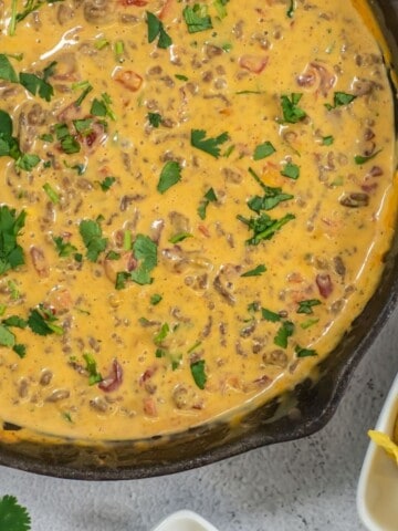 Ground beef queso dip with Rotel and Velveeta cheese in a large skillet.