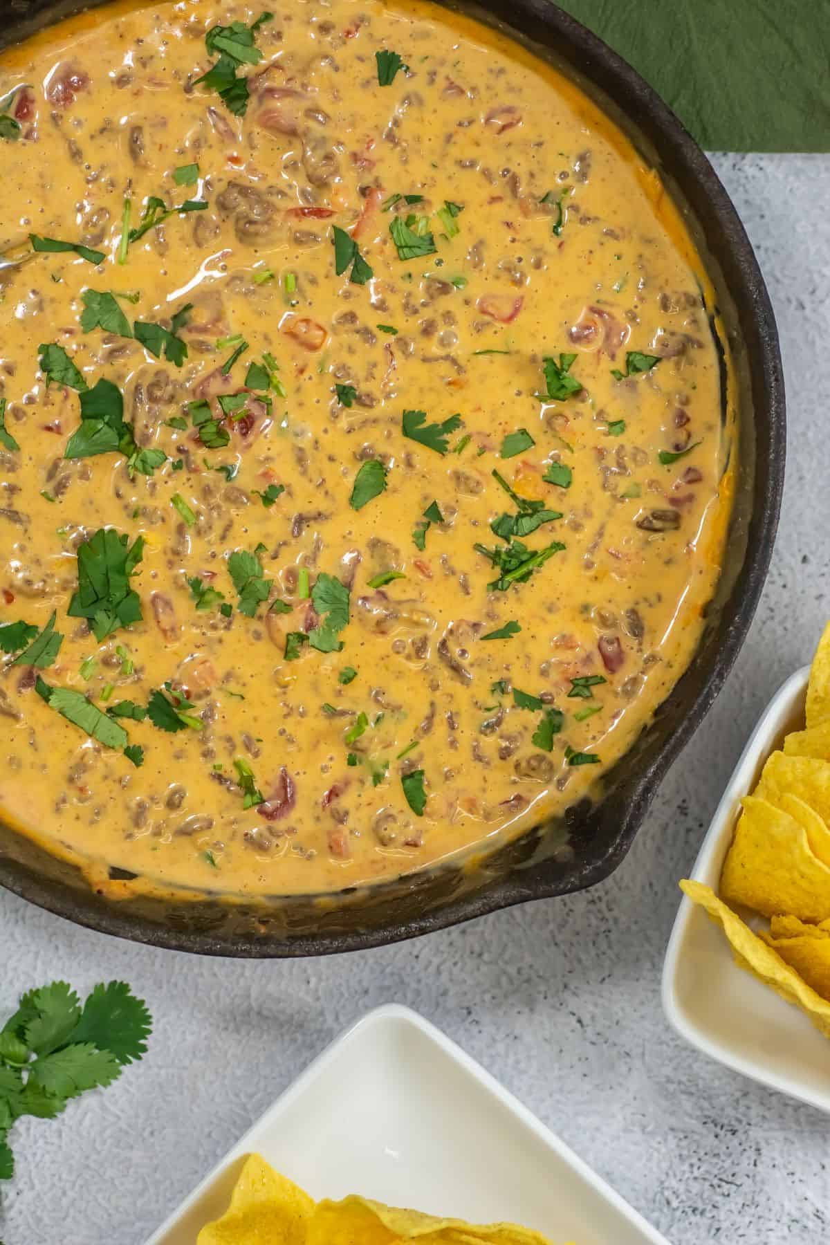 Ground beef queso dip with Rotel and Velveeta cheese in a large skillet.