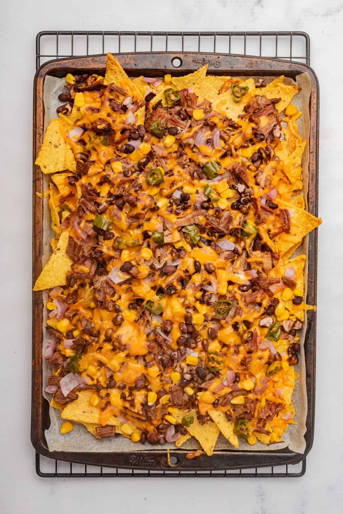 Baked sheet pan brisket nachos loaded with toppings.