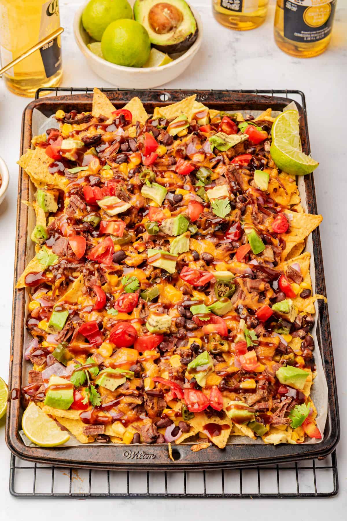 Baked sheet pan nachos loaded with shredded brisket and toppings.