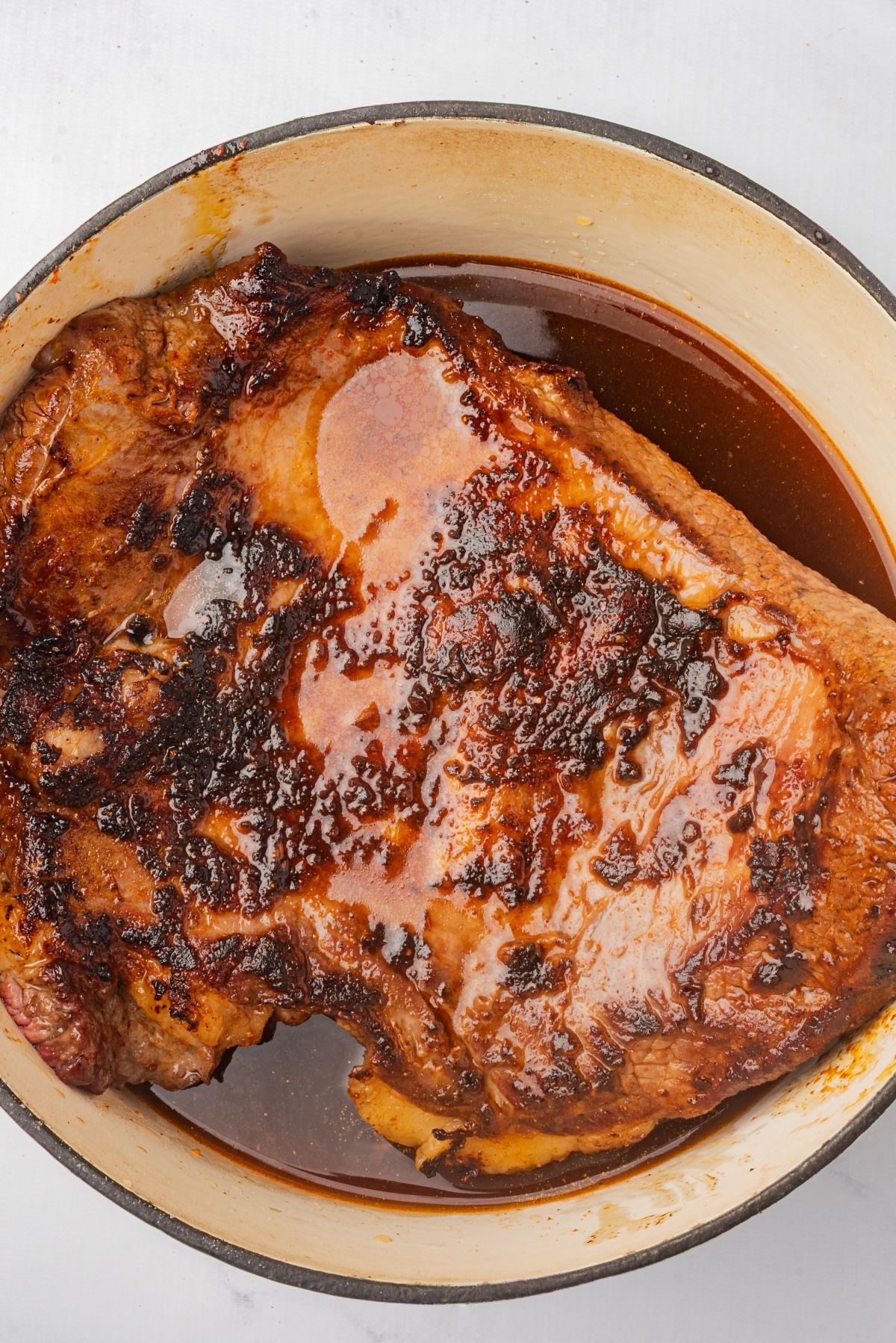 Seared beef brisket in a Dutch oven with braising liquid.