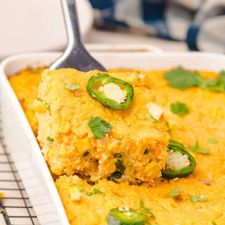 Square of jalapeno corn casserole on a spatula getting removed from the baking dish.