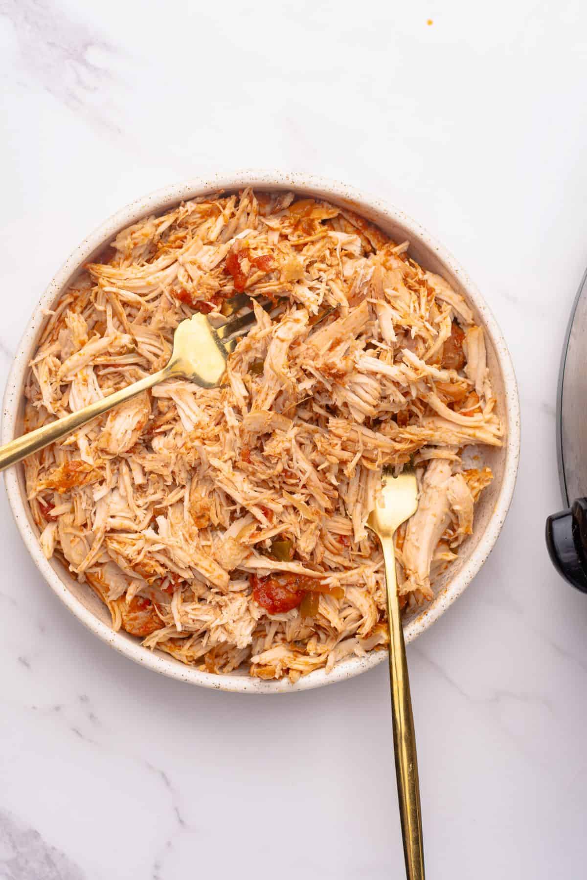 Shredded salsa chicken in a bowl with two forks.