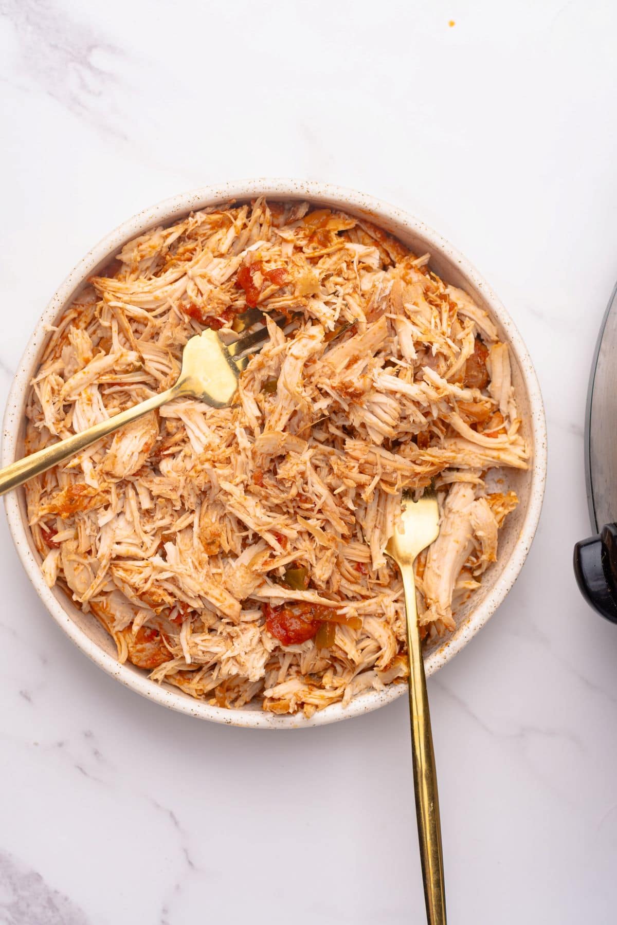 Shredded chicken in a bowl with two forks.