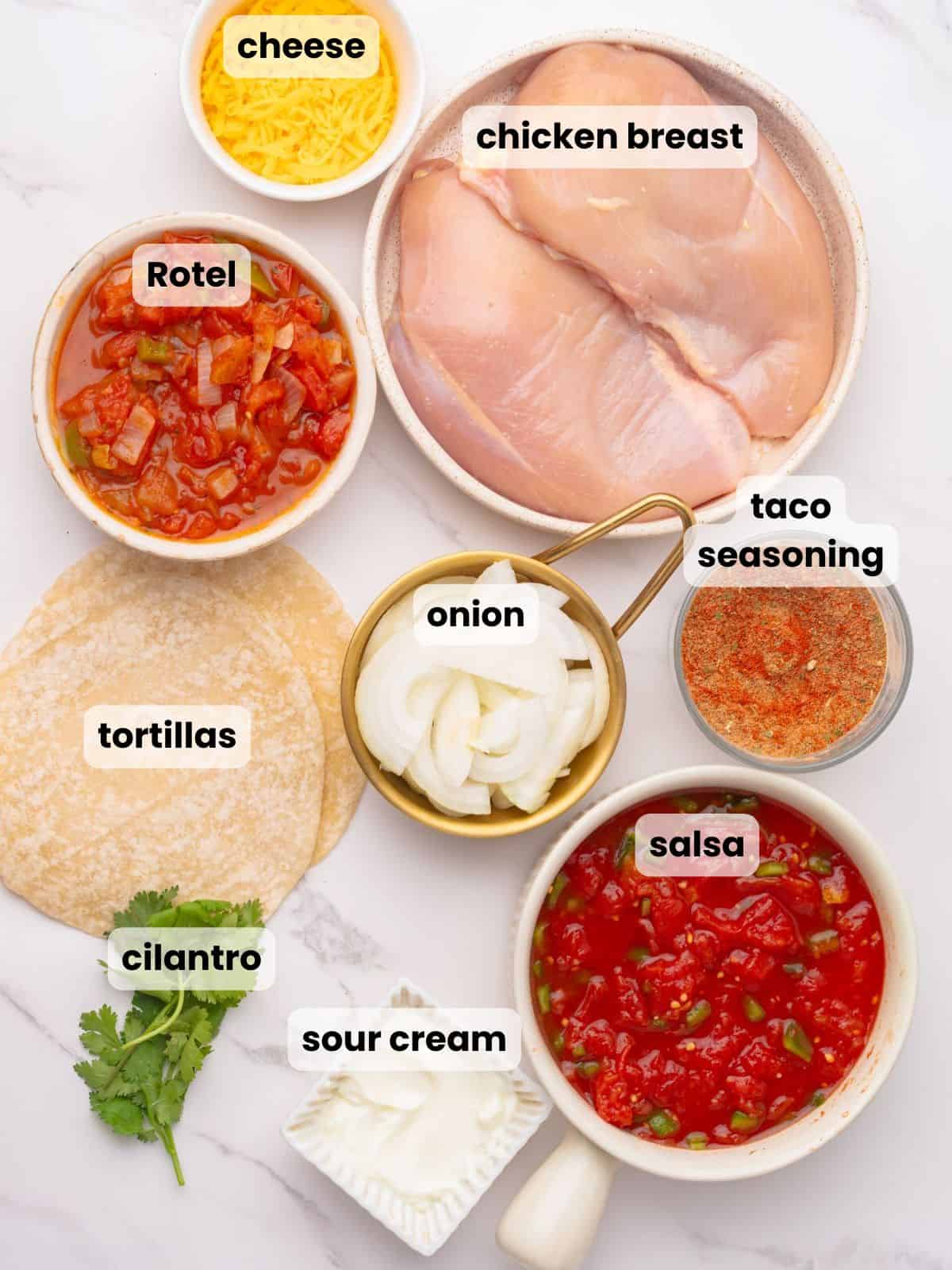 Ingredients needed to make this slow cooker chicken tacos recipe are on a marble countertop.