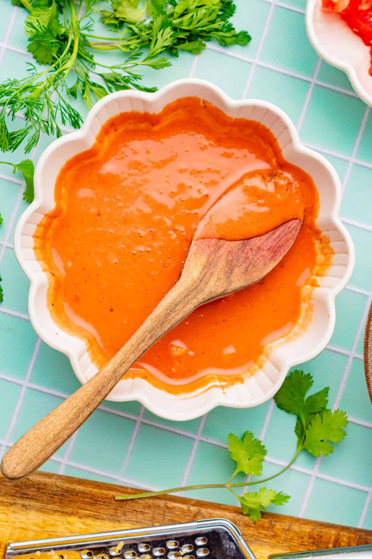 Homemade chipotle crema in a bowl with a wooden spoon.