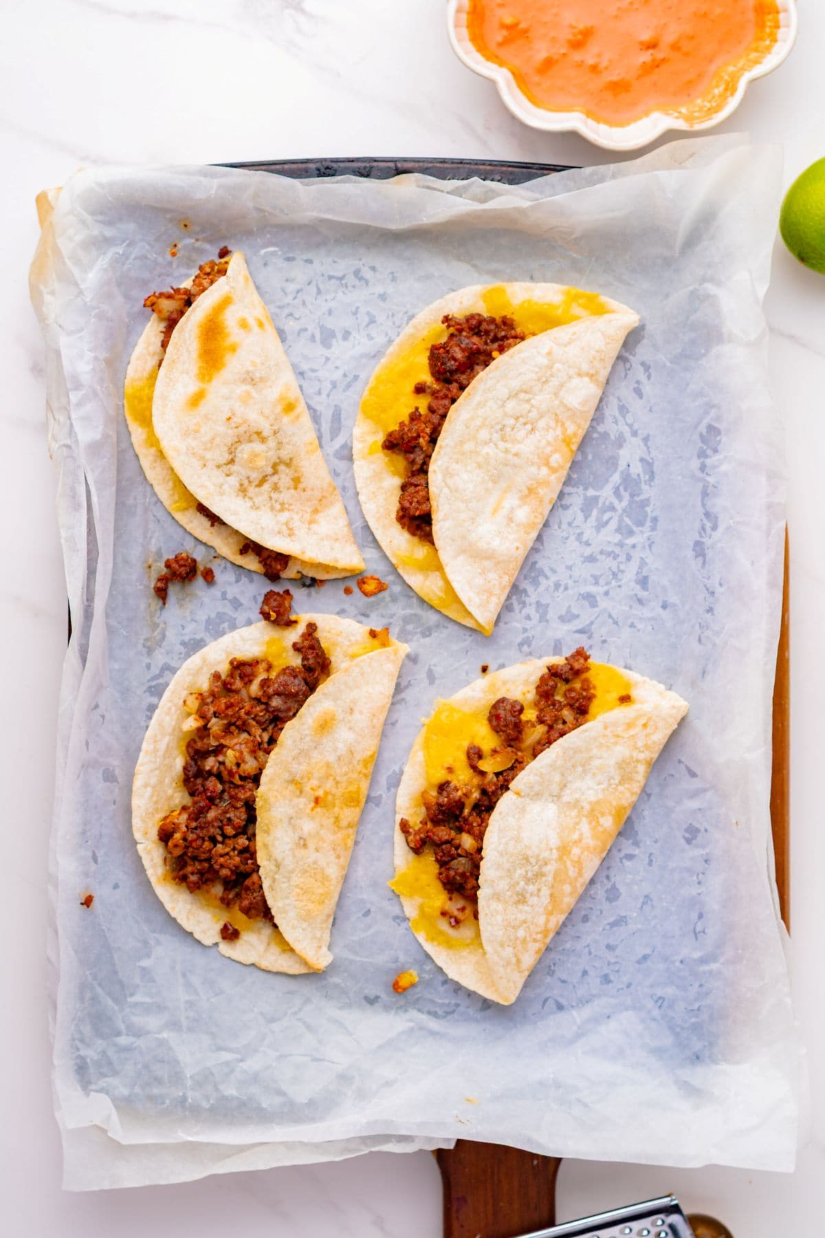 Folded baked beef and cheese tacos on a sheet pan.