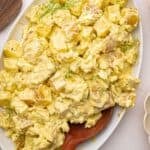 Mustard potato salad on a platter with a wooden spoon.